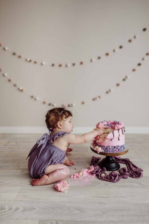 Cake Smash Session - baby girl grabs a handful of cake to eat