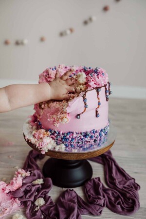 Cake Smash Session - baby girl grabs a big handful of pink icing