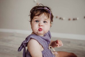 Cake Smash Session - baby girl pouts with a mouthful of pink icing