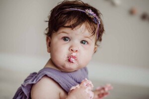 Cake Smash Session - a baby girl pouts with a mouthful of pink icing