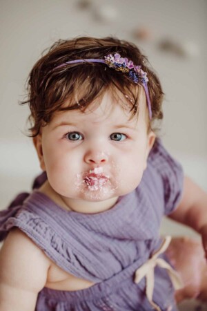 Cake Smash Session - a baby girl smiles with a mouthful of pink icing