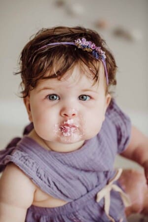 Cake Smash Session - a baby girl smiles with a mouthful of pink icing