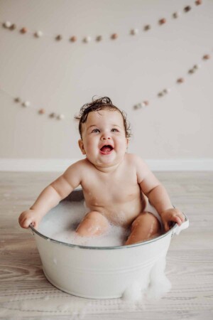 Cake Smash Session - a baby girl smiles as she enjoys a bubble bath