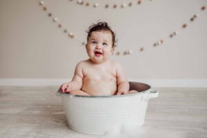 Cake Smash Session - baby girl sits in a bath tub after her cake smash