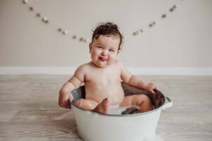 Cake Smash Session - baby girl sits in a bath tub and blows raspberries