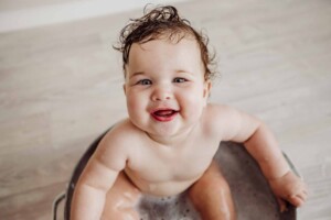 Cake Smash Session - baby girl sits in a bath tub and smiles