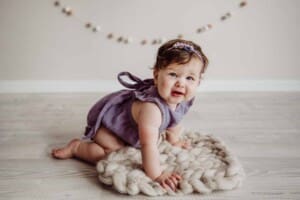 Cake Smash Session - baby girl crawls on a cream wool blanket