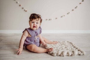 Cake Smash Session - baby girl sits on a cream wool blanket