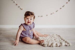 Cake Smash Session - baby girl sits on a cream wool blanket