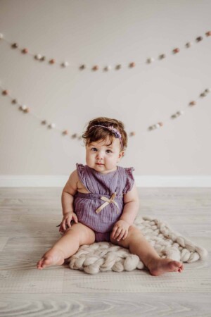 Cake Smash Session - a baby girl sits on a cream wool blanket