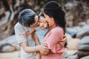 Family Photographer - parents kiss their baby girls cheeks