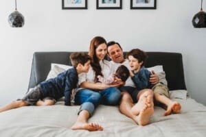 Baby Photography - a family sit on a bed and gaze upon their newborn baby
