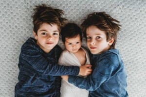 Baby Photography - little boys lay down cuddling their newborn sister between them