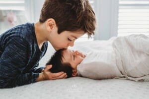Baby Photography - a little boy kisses his newborn sister on the head