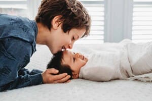 Baby Photography - a little boy kisses his newborn sister on the head