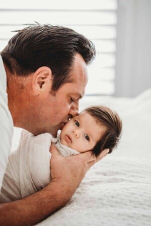 Baby Photography - a father kisses his newborn daughter gently on the cheek