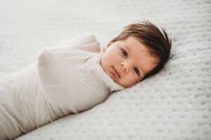 Baby Photography - newborn girl laying awake on a white blanket
