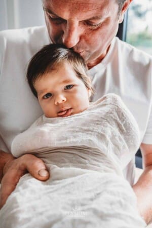 Baby Photography - a father kisses the head of his newborn baby girl