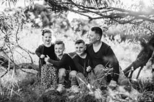 4 siblings sit together on a low tree branch
