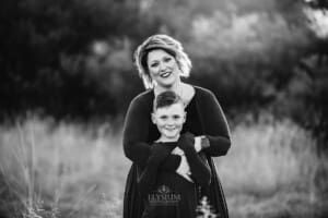 A mother cuddles her son at sunset