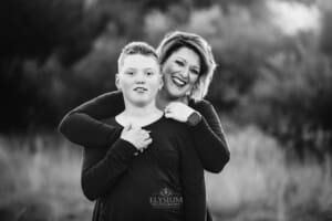 A mother cuddles her son at sunset
