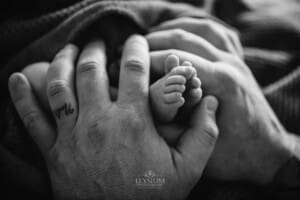 Newborn Photograph - a fathers big hands hold his baby's tiny feet