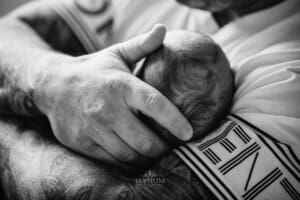Newborn Photograph - a fathers hands cradle his baby's head