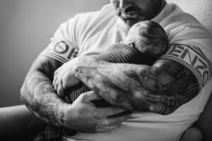 Newborn Photograph - a fathers arms hold his tiny baby boy