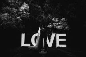 Burnham Grove Wedding - the bride and groom kiss in front of the LOVE sign