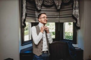Burnham Grove Wedding - groom does up his tie during prep