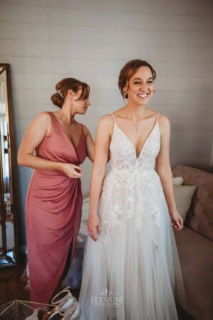 Burnham Grove Wedding - bridesmaid does up the bridal gown