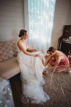 Burnham Grove Wedding - bridesmaid helps the bride with her shoes