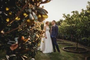 Burnham Grove Wedding - newlyweds hold hands as they walk through the orchard