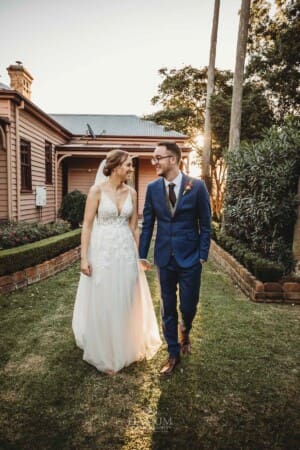 Burnham Grove Wedding - newlyweds hold hands as they walk past the homestead