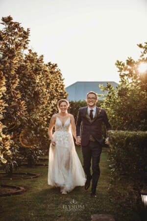 Burnham Grove Wedding - newlyweds hold hands as they run through the orchard