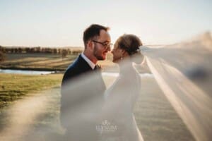 Burnham Grove Wedding - newlyweds cuddle as the brides veil sweeps around them
