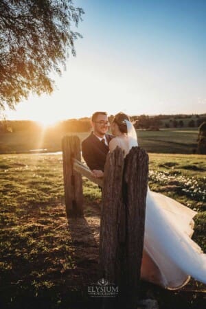 Burnham Grove Wedding - bride and groom lean against a fence rail at sunset