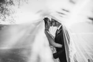 Burnham Grove Wedding - bride and groom kiss standing under the bridal veil