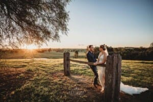 Burnham Grove Wedding - bride and groom lean against a fence rail at sunset