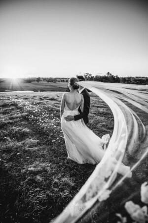 Burnham Grove Wedding - newlyweds cuddle as the brides veil sweeps around them