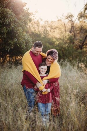 Parents cuddle their son wrapped in a blanket