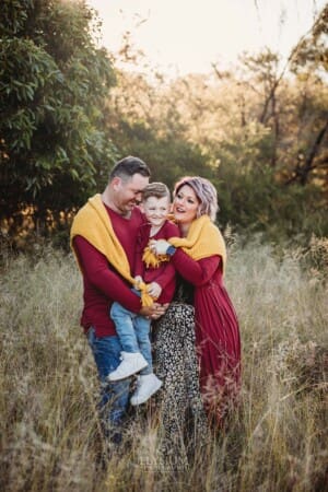 Parents cuddle their son wrapped in a blanket