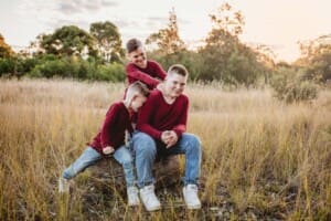 3 boys wrestle together in a grassy field