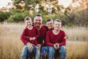 A father sitting on a log with his 3 sons