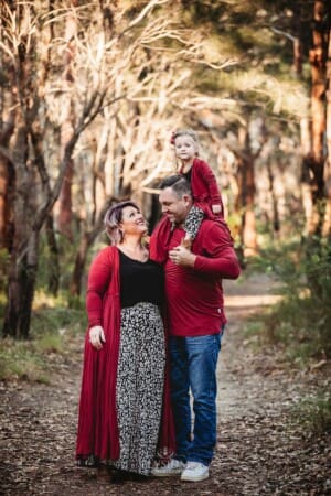 Parents cuddle, their little girl sits on dad's shoulders