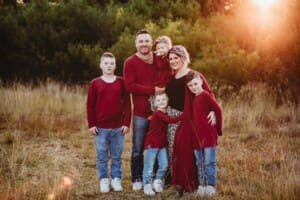 A family snuggle together in a grassy field at sunset