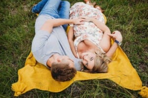 Maternity Photographer - a couple lay on a blanket in a grassy field