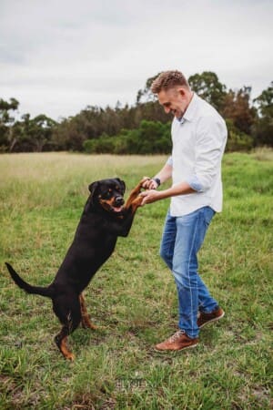 Maternity Photographer - a man dances with his dog in a grassy field