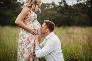 Maternity Photographer - a husband kisses his wife's pregnant belly