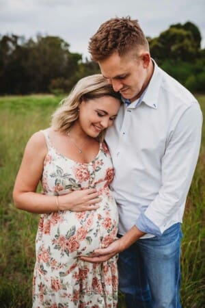 Maternity Photographer - a man hugs his pregnant wife and holds her belly